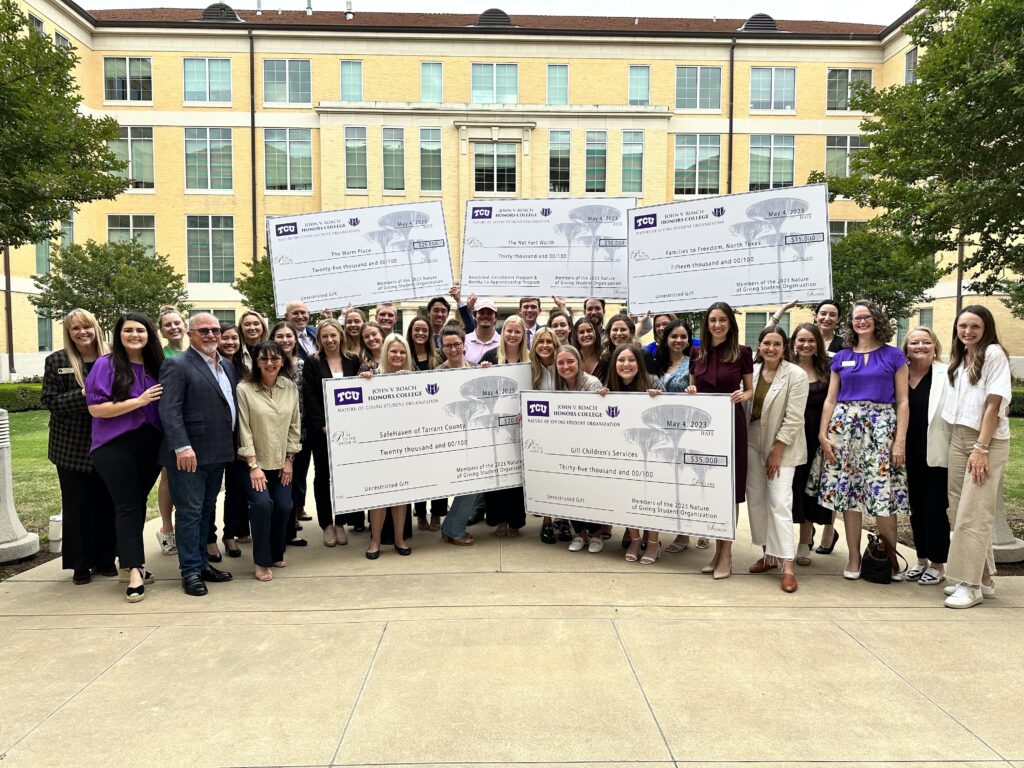 Group of people holding large checks